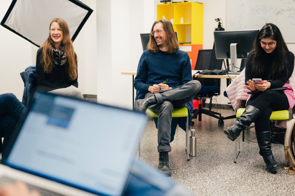 Drei junge Menschen bei einem Gespr&auml;ch in einem modernen B&uuml;ro.