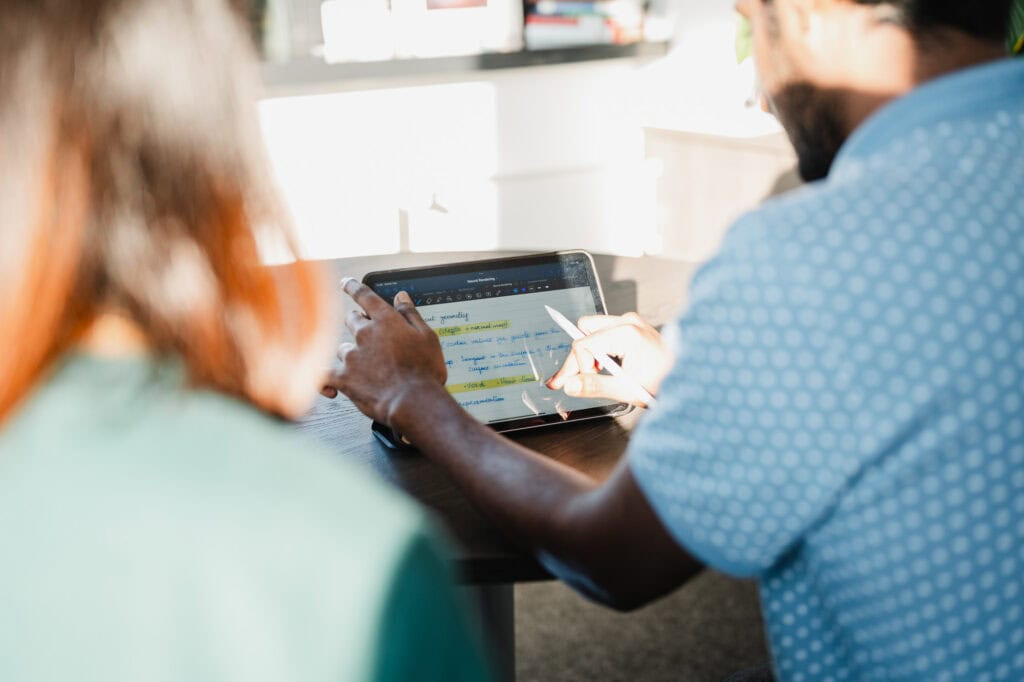 Menschen arbeiten an einem Tablet mit Datenanalyse in einem modernen B&uuml;ro.