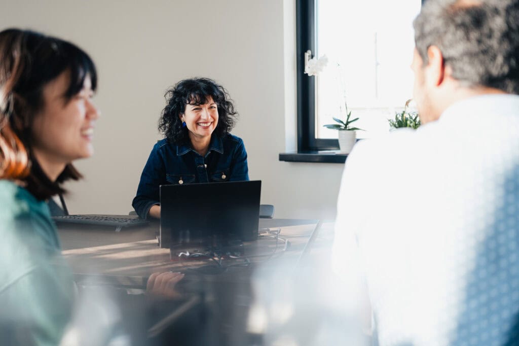 Drei Menschen im Gespr&auml;ch bei einem Meeting in einem modernen B&uuml;ro.