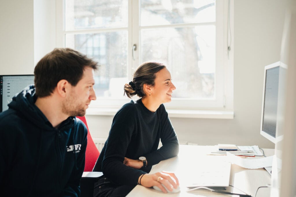 AI made in Germany: Ein zukunftsweisender Bildpool für die Konrad Zuse Schools (DAAD) 20 Zwei Personen bei einer Besprechung im Büro vor einem Computer.