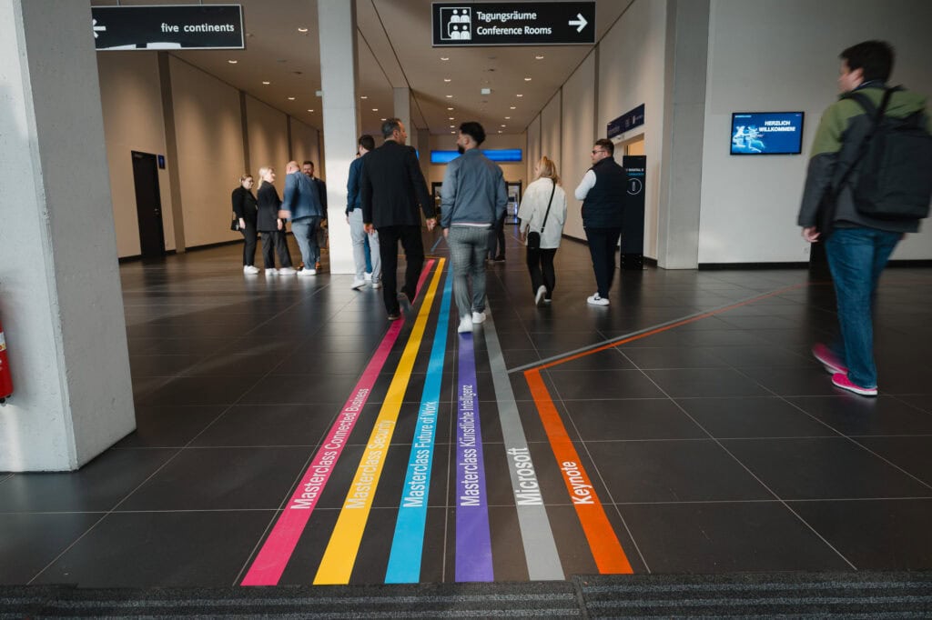 Digitalisierung im Norden: Das Digital X Regional Event 2025 4 Menschen im Flughafen mit farbigen Markierungen auf dem Boden.